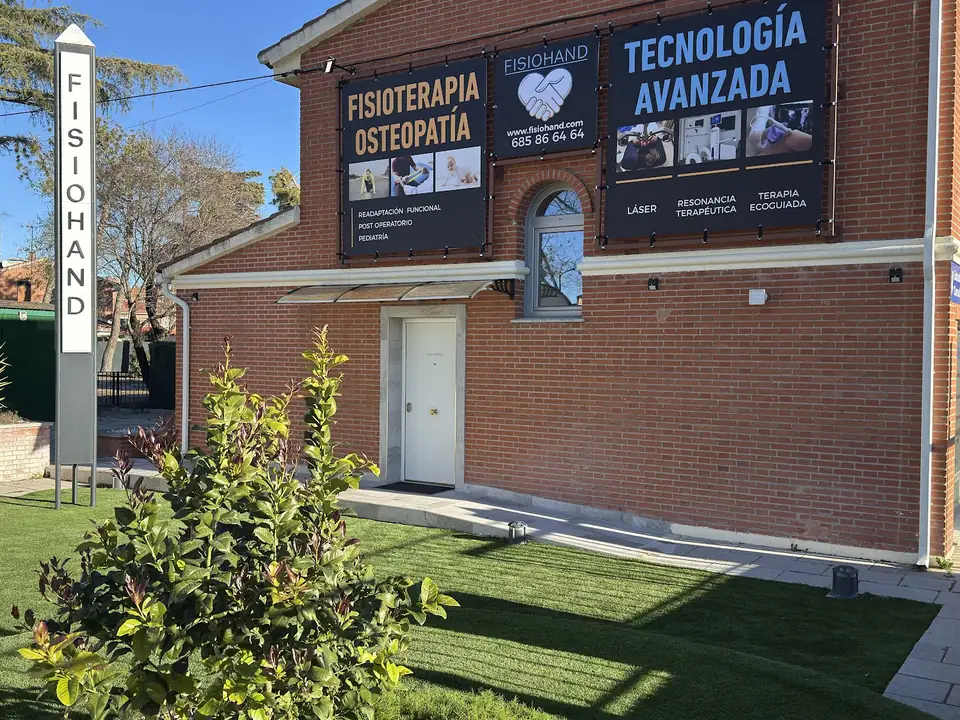 La fachada de ladrillo de Fisiohand, con el tótem de su nombre y los carteles de fisioterapia, osteopatía y tecnología avanzada